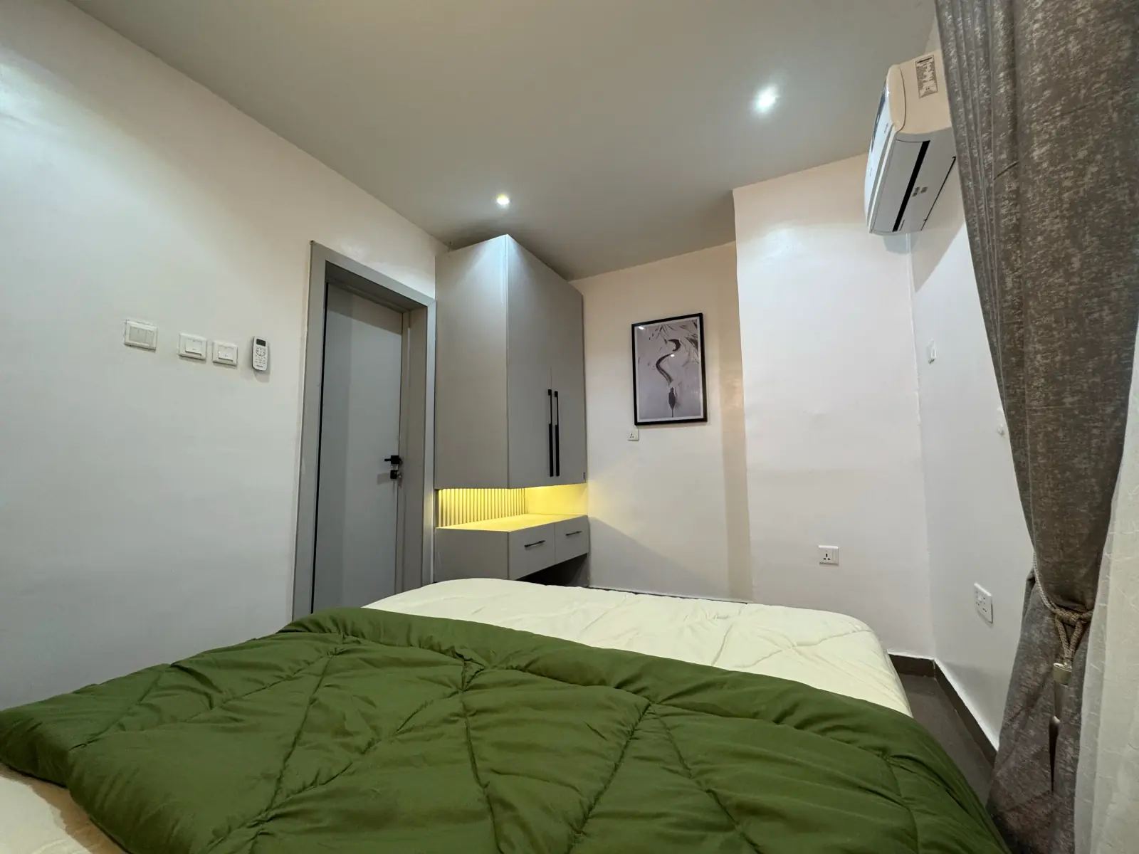 The second bedroom from the doorway, with green bedding and a wall-mounted AC