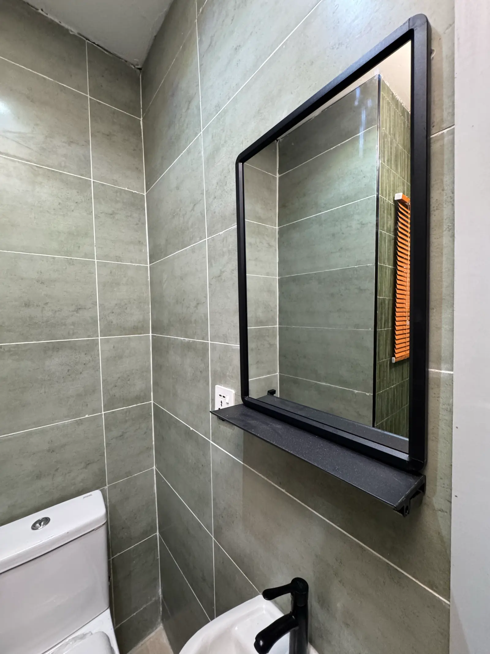Black-framed mirror and basin against grey tiles