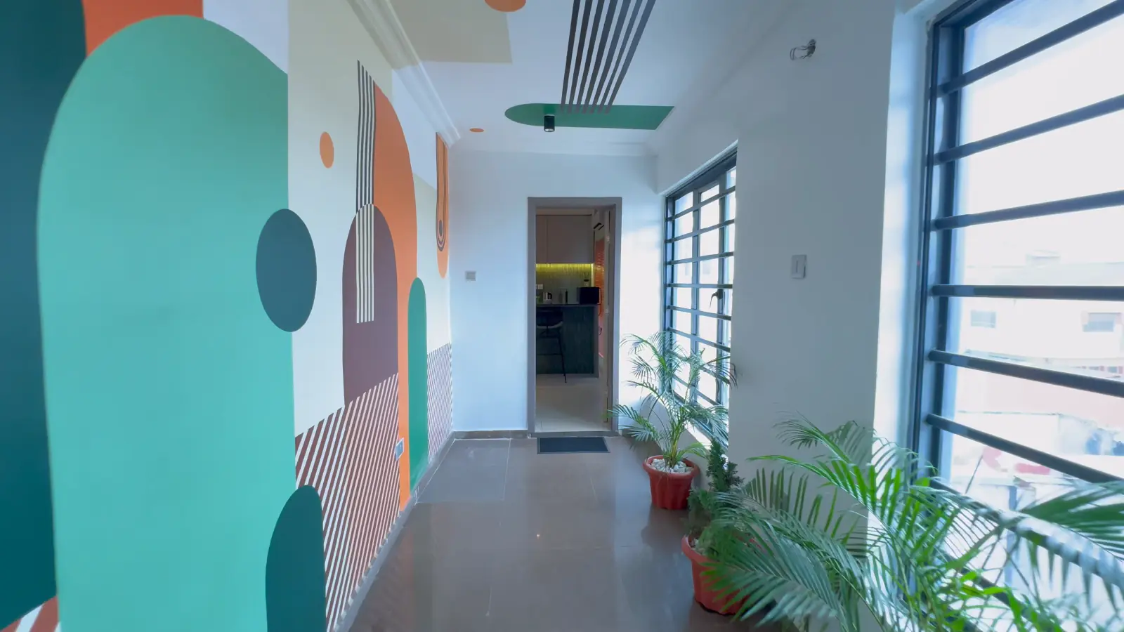 White corridor with a painted mural of green, mint, orange and plum arches, circles and stripes