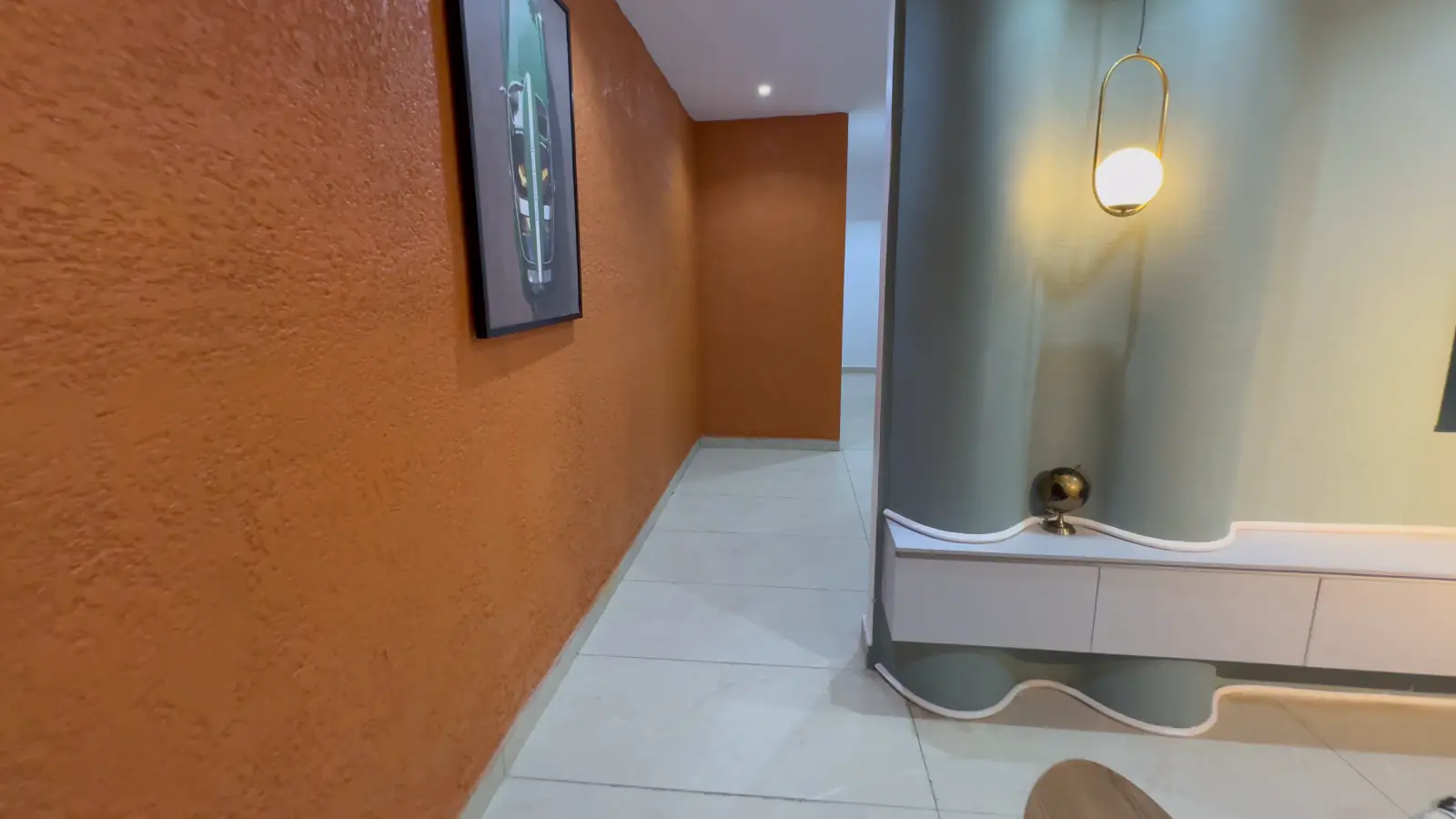 Hallway with a textured burnt-orange wall leading to the bedrooms